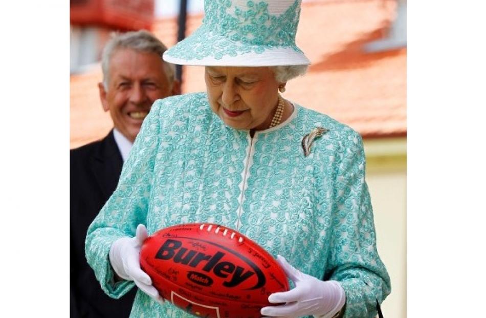 Queen Elizabeth holds an Australian rules football during her visit to Clontarf Aboriginal...