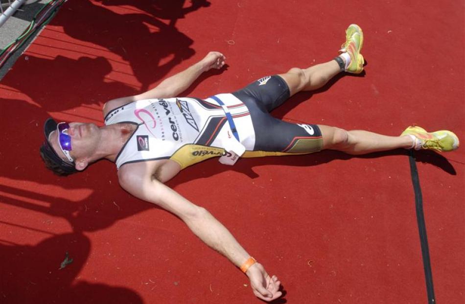 Race winner Aaron Farlow, from Australia, collapses at the finish of Challenge Wanaka 2012. After...