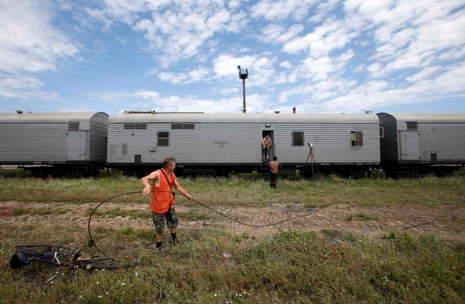 Railway employees work near refrigerator wagons, said to contain bodies of passengers of the...