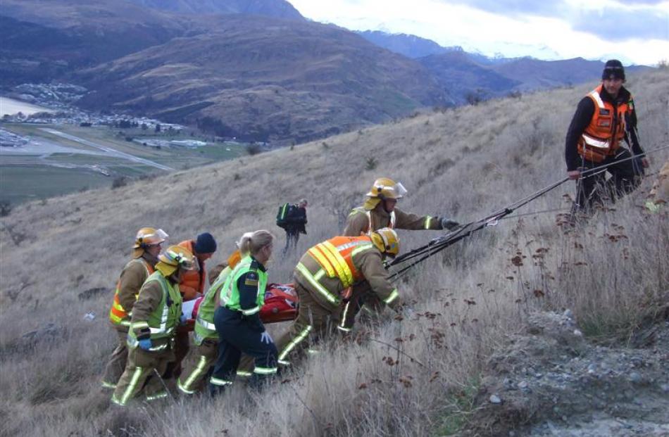 Rescue crews lift an injured passenger  to a waiting ambulance from the site of a crash where a...