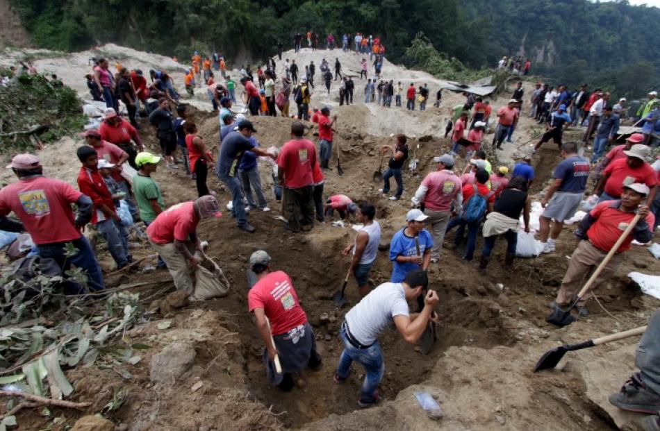 Rescue team members and volunteers search for survivors of the mudslide in Santa Catarina Pinula,...