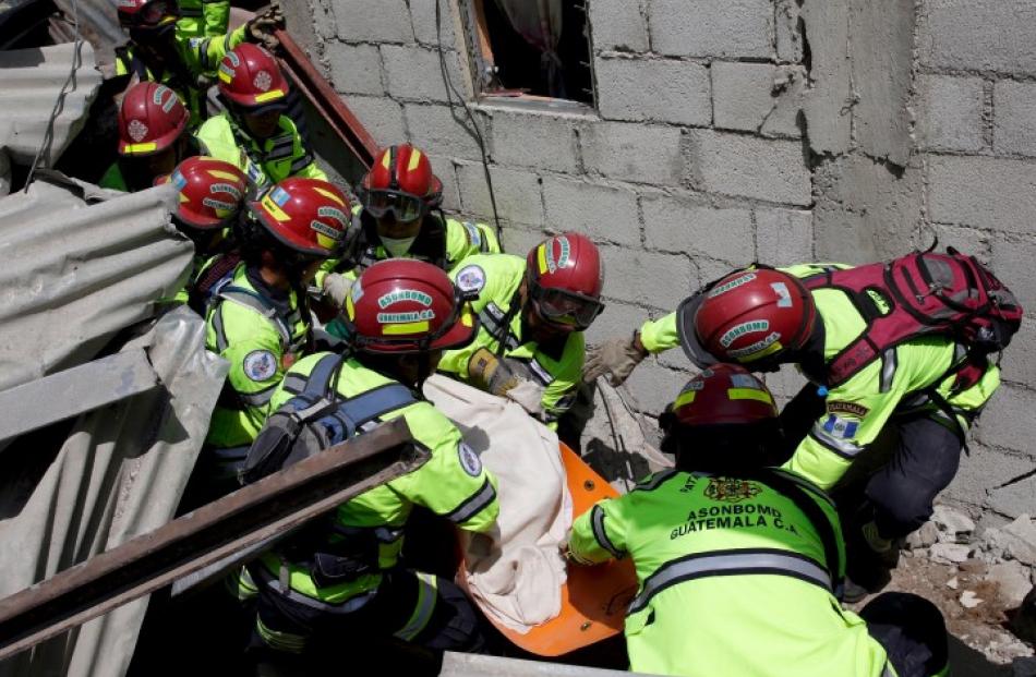 Rescue team members retrieve the body of a mudslide victim in Santa Catarina Pinula, on the...