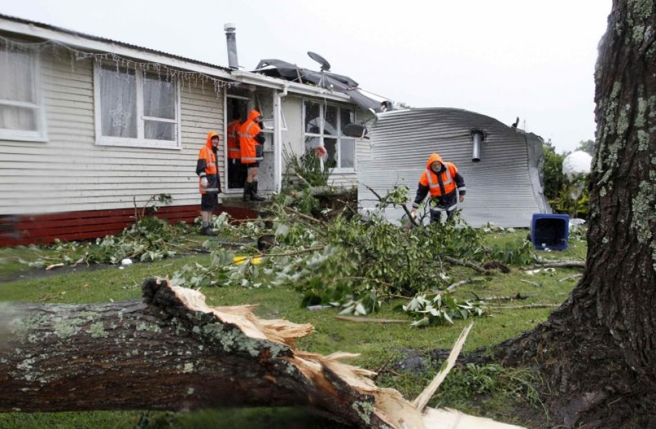 Rescue workers search amid the devastation in the suburb of Hobsonville after a tornado went...