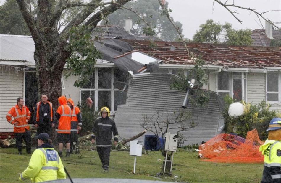 Rescue workers survey a site in the west Auckland suburb of Hobsonville after a tornado went...