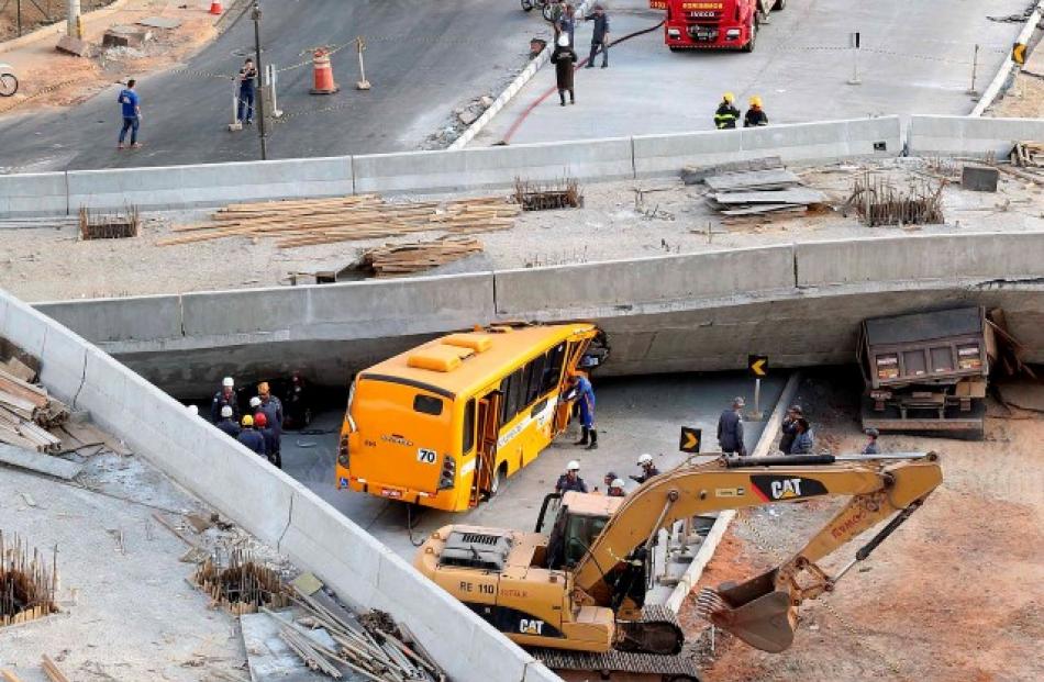 Rescue workers try to reach vehicles trapped underneath a bridge that collapsed while under...