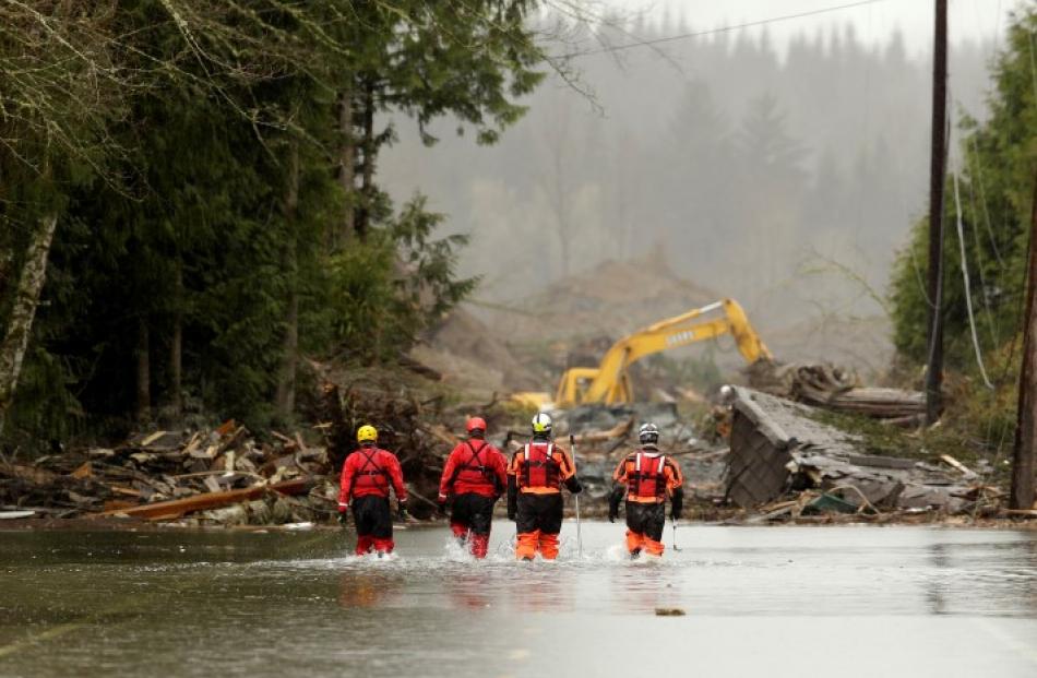 Rescuers walk in floodwaters on Highway 530 as search work continues after the mudslide that...