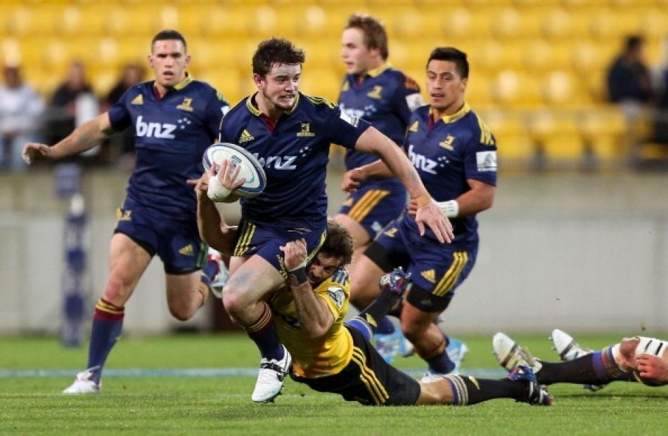 Richard Buckman of the Highlanders is tackled by Conrad Smith of the Hurricanes during the round...