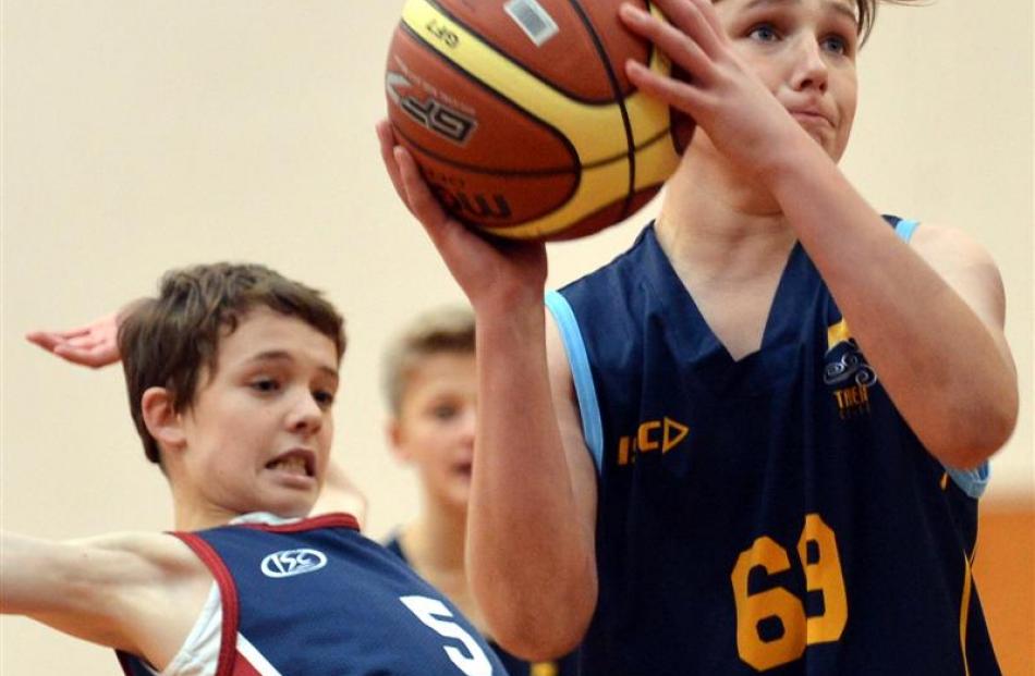 Riley Dixon (Taieri College) shoots for goal while Nathaniel Peacock (Kavanagh College) looks on...