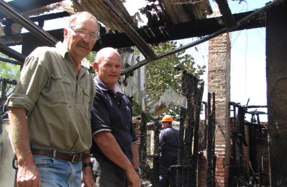 Sam Leask (left) inspects the burnt-out ruins of his childhood home in Ophir with Ken Lake, who...