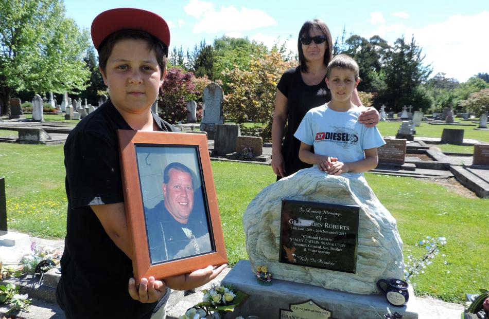 Sean Roberts (10, left) at his father's grave yesterday, with his mother Mel Pipson and and...