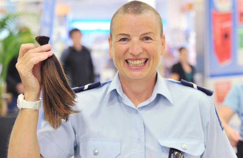Senior Constable Helen Fincham-Putter gets her head shaved by hairdresser Jordan Hill at the...