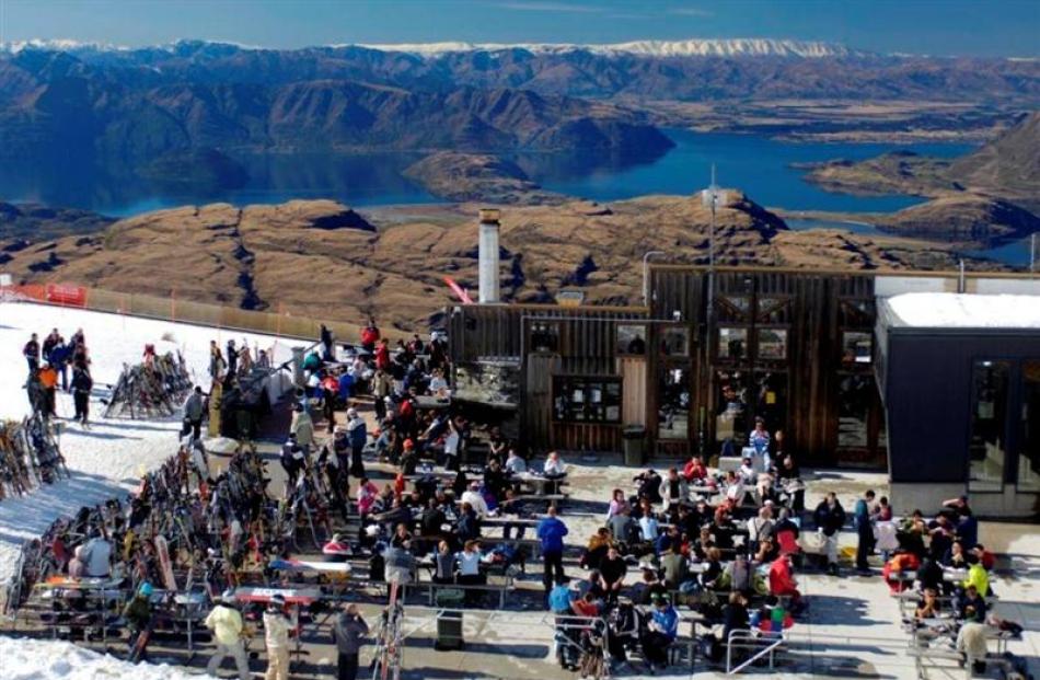 Skiers enjoy the sun outside the Treble Cone ski area base building in September 2010. Skiing is...