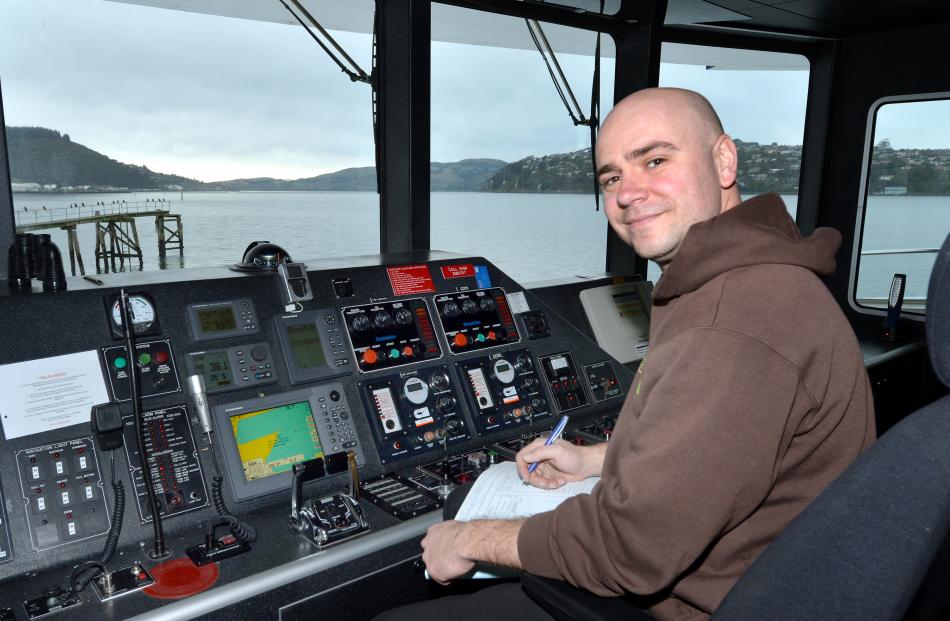 Skipper Turgut Ortabas completes a logbook in the catamaran's bridge while the vessel is moored...