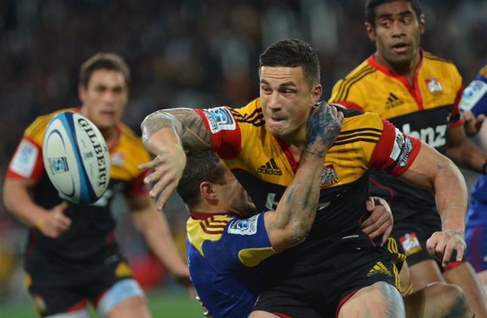 Sonny Bill Williams, of the Chiefs, offloads in the tackle of  Highlander  Tamati Ellison. Photo...
