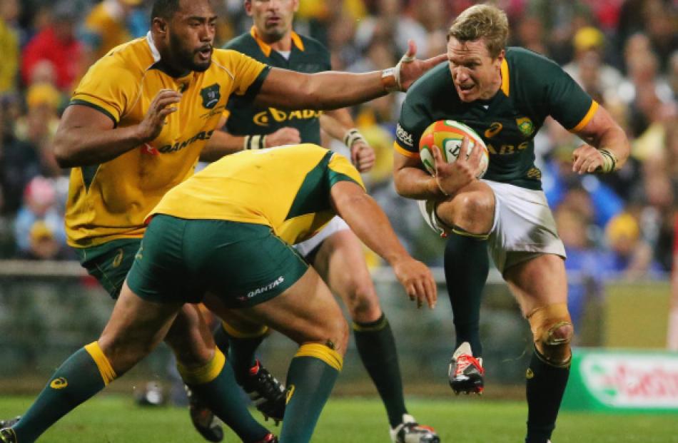 Springbok captain Jean de Villiers (R) tries to get past the Wallabies defence during their match...