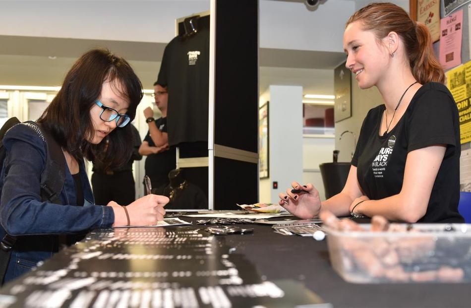 Student Qiao Zhang signs on for Thursdays in Black, a campaign against sexual violence, as Ella...