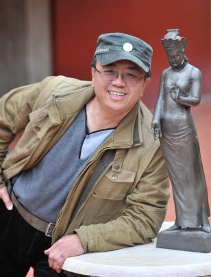 Sun Qi (52) with one of his bronze figurines that represent the search for serenity through faith...