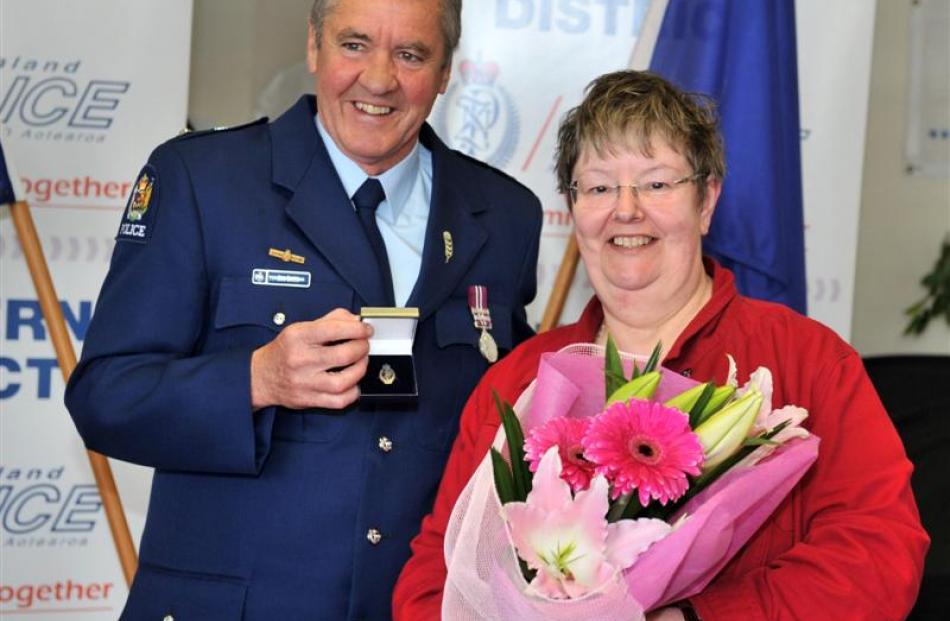 Superintendent Bob Burns presents retired police administrator June Holden with her medal for 42...