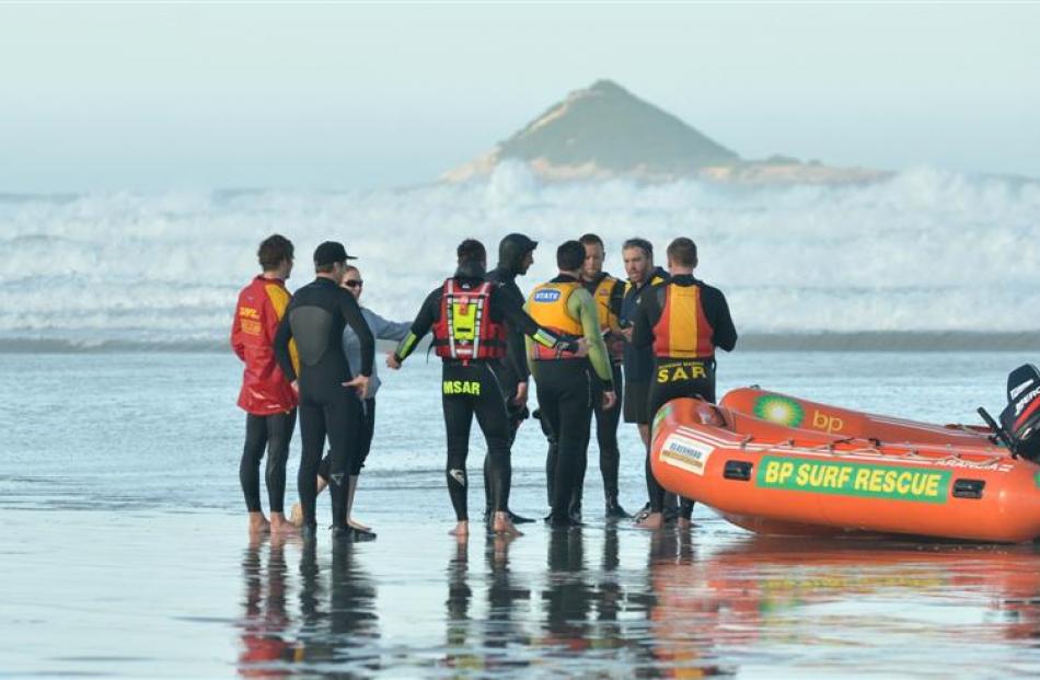 Surf life-savers and two of the four surfers rescued yesterday chat after a jet ski and the...