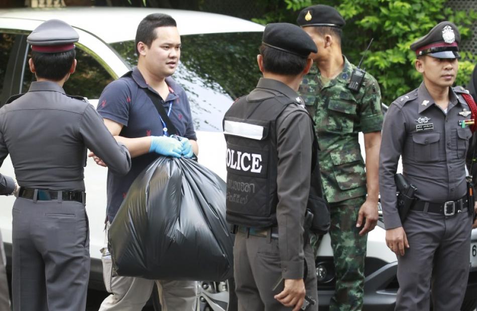 Thai Royal Police officials remove evidence from the site where a suspect of the recent Bangkok...