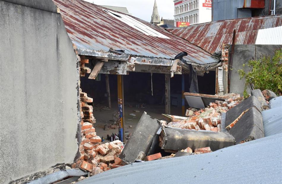 The brick and plaster rubble of a wall at 386 Princes St, Dunedin, lies on a neighbouring roof...