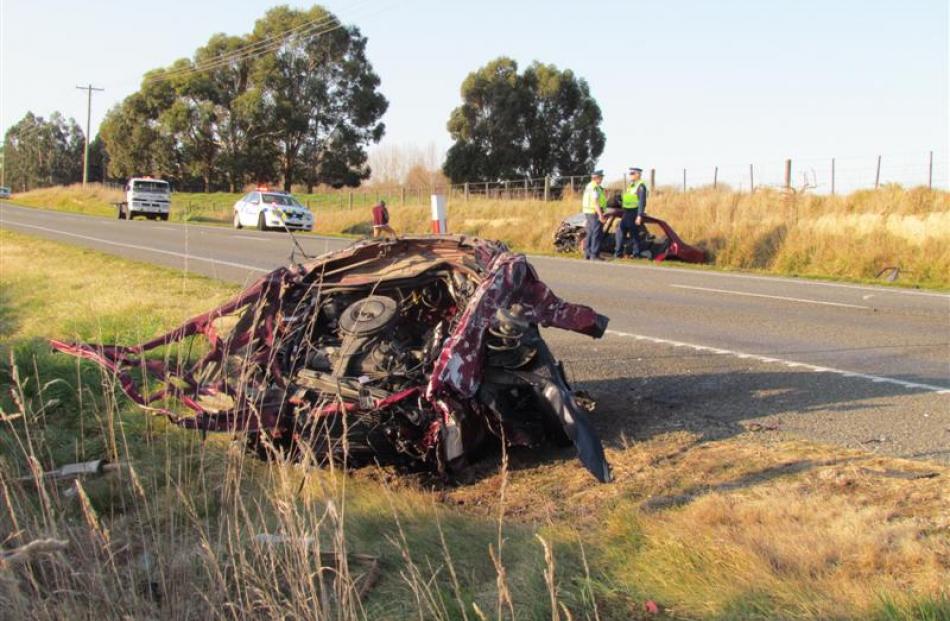 The front of a Mazda Familia car sits beside  State Highway 1 after it broke away from the rest...