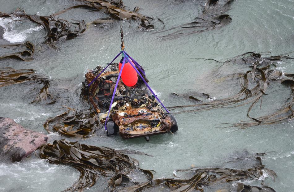 The remains of a Volkswagen Touareg is lifted clear of the water yesterday near Curio Bay  on the...