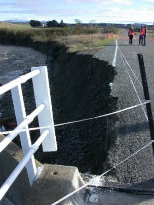The washed-out Kauru River bridge approach on Kakanui Valley Rd is assessed yesterday by (from...