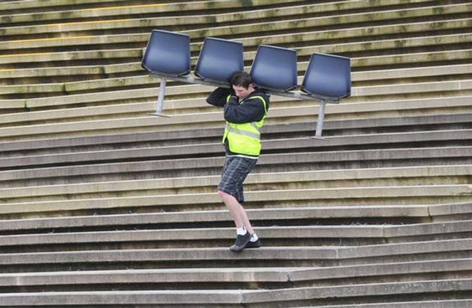 Thomas Smith (18), of Mosgiel, carries seats at the Carisbrook garage sale in Dunedin on Saturday.