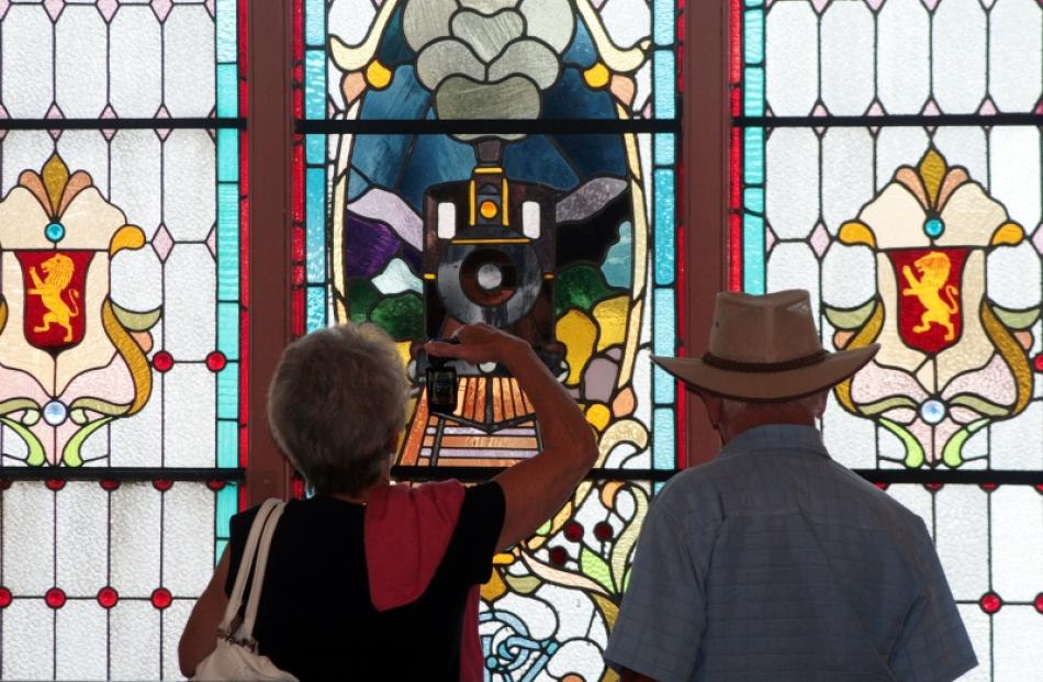 Tourists get a close-up photo of a stained glass window at the Dunedin Railway Station