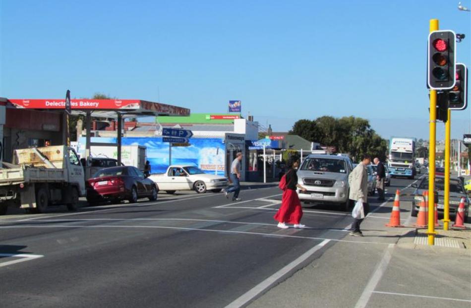 Traffic starts to back up as two pedestrians use the recently installed crossing lights in north...