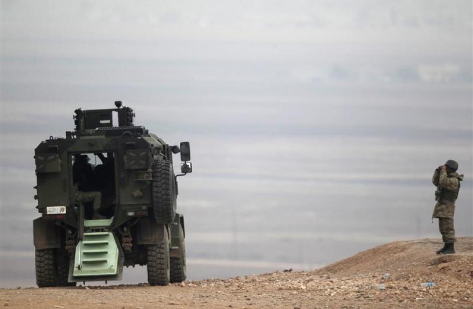 Turkish soldiers watch fighting between Kurdish fighters and Islamic State militants near the...