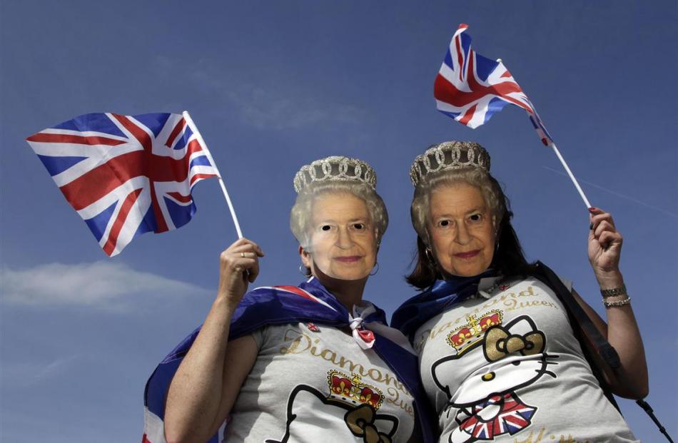 Two women, wearing masks depicting Britain's Queen Elizabeth, pose for a picture during a Jubilee...