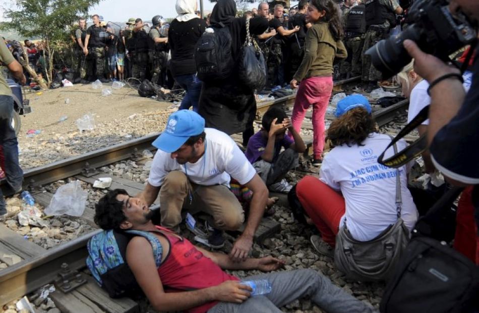 UN workers help a man who collapsed at the border dividing Macedonia and Greece. REUTERS/Ognen...