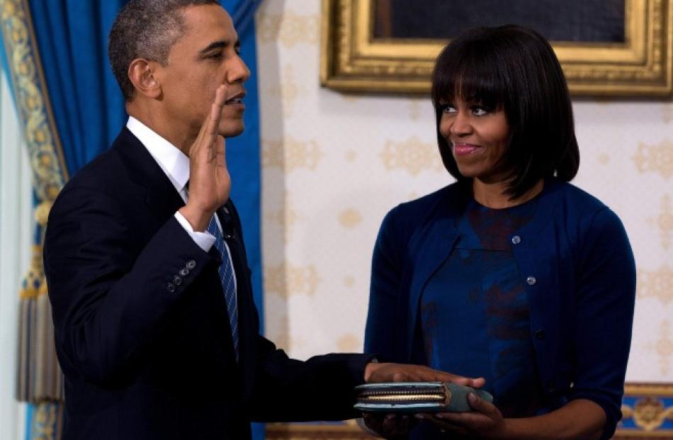 US President Barack Obama takes the oath of office as first lady Michelle Obama holds a bible...
