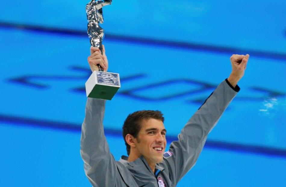 US swimmer Michael Phelps holds up his award recognising him as the most decorated Olympian at...