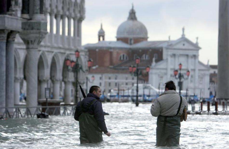 Two men wade through a flooded St. Mark's Square, in Venice, northern Italy, on Monday. Photo...