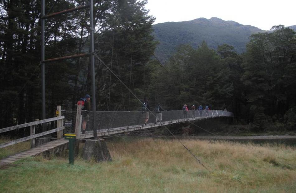 Walkers cross a swing bridge over the Clinton River, just after leaving Glade House where they...