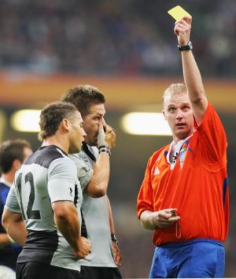 Wayne Barnes shows a yellow card to All Black second five-eighth Luke McAlister during their...