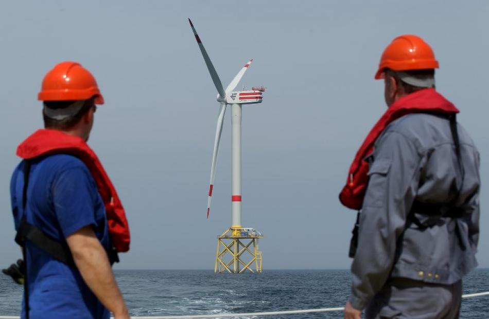 Workers look out at turbines at the Alpha Ventus offshore windpark approximately 70km north of...