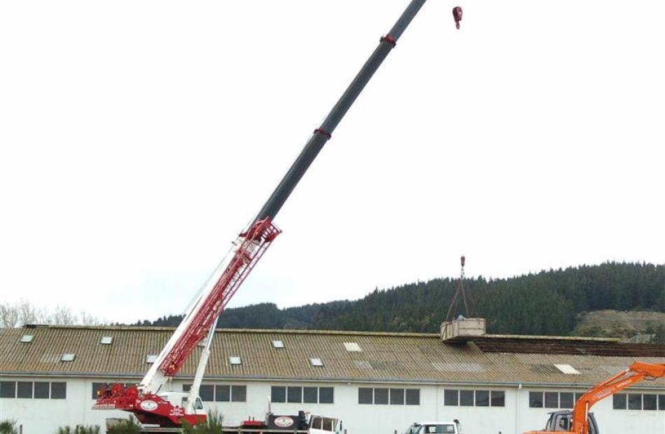 Workers remove roofing panels from a building in the construction zone. Photos by Gerard O'Brien.