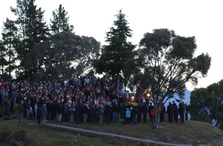 A crowd gathers on the rocky headland and cenotaph flagpole at Lake Hawea for an Anzac Day dawn...