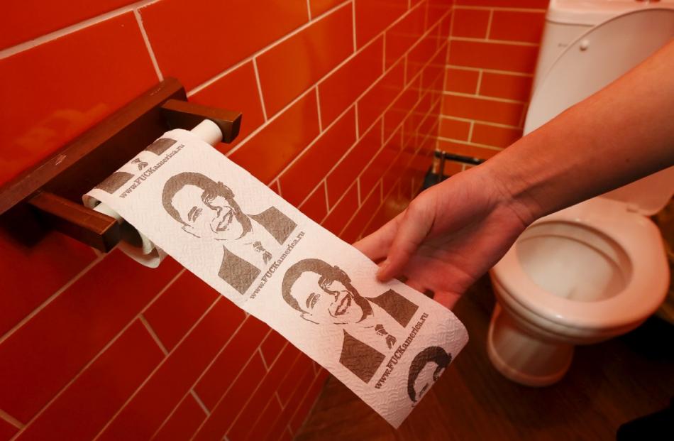 A customer pulls on a roll of toilet paper depicting U.S. President Barack Obama at the ...