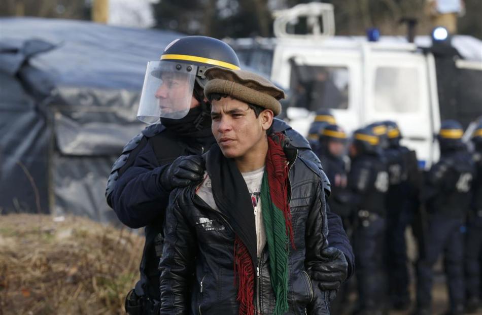 A French CRS riot policeman apprehends a young Afghan during a protest by migrants against the...