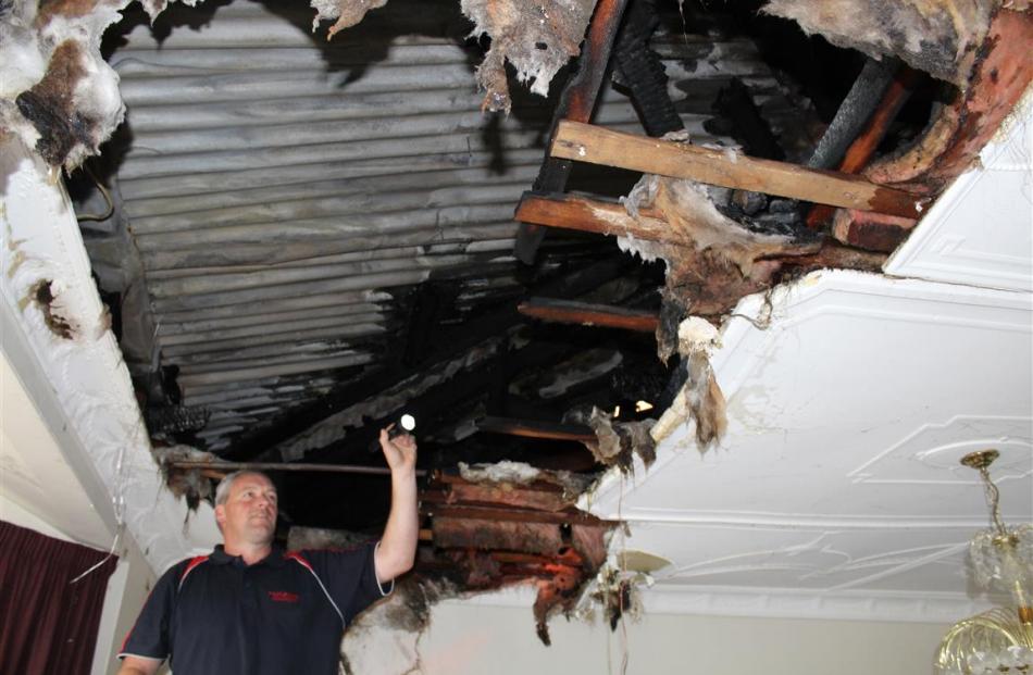 Chris Hope, of Phoenix Services, inspects fire damage in the ceiling of a motel unit at the Tower...