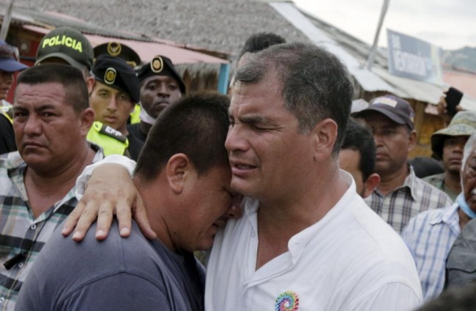 Ecuador's President Rafael Correa (R) embraces a resident  in the town of Canoa after the...