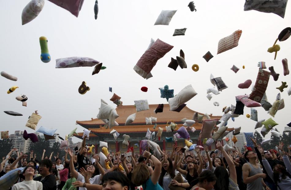 Participants throw their pillows during the International Pillow Fight Day at Liberty Square, in...