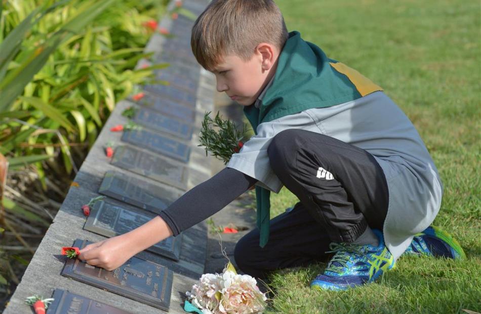 Will Moyle (7), of Green Island, places a posy on a returned serviceman’s grave during an Anzac...