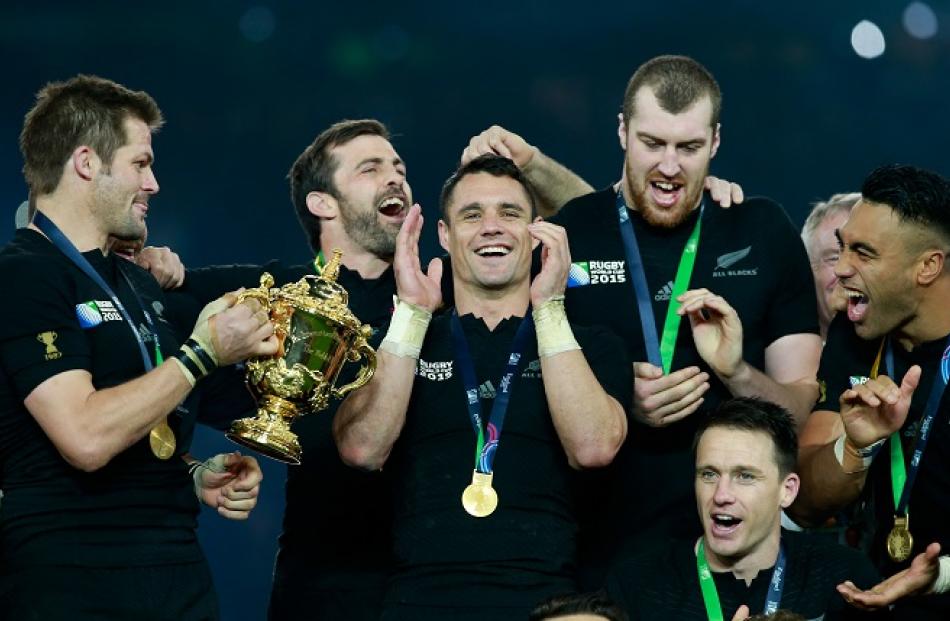 Surrounded by teammates, Dan Carter (C) celebrates the All Blacks' World Cup victory over...