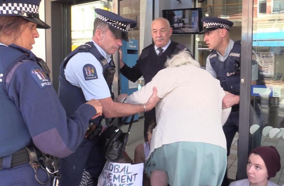 Police help an older woman to negotiate  climate change protesters blocking the entrance to an...